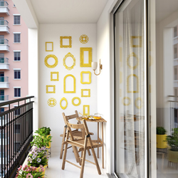 A balcony with a chair and a table and yellow decorative frames in the background