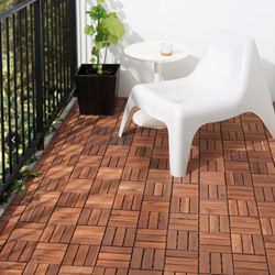 White chair placed on a balcony with wooden floor with a tall plant on the background