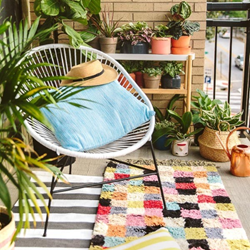 A summery chair and  a colourful rug on a balcony  with plants