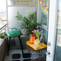 A small balcony with a tray of drinks and a green BBQ