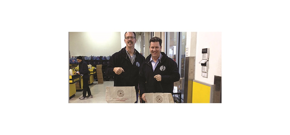 Town of Cochrane economic development officer Robert Kalinovich and economic development manager Mike Korman hand out Proudly Cochrane reusable shopping bags at a local grocery store. Photo courtesy Town of Cochrane.