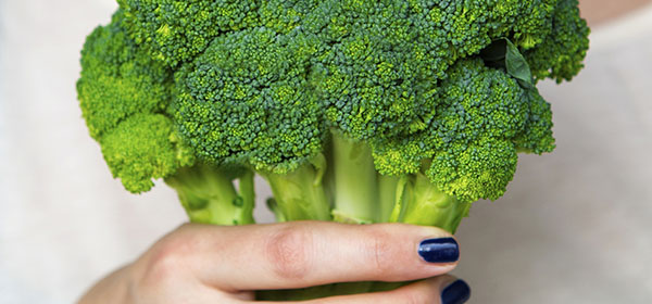 closeup of woman holding broccoli in her hand