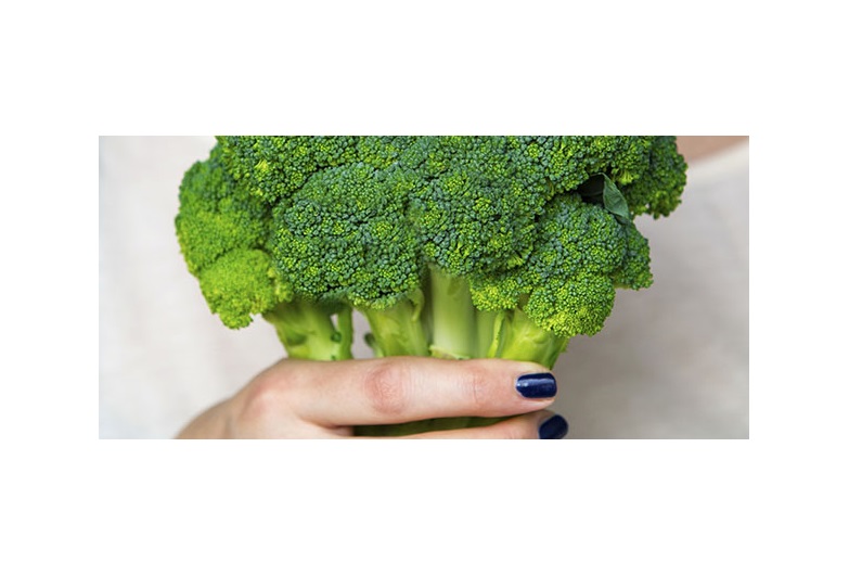 closeup of woman holding broccoli in her hand