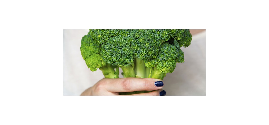 closeup of woman holding broccoli in her hand