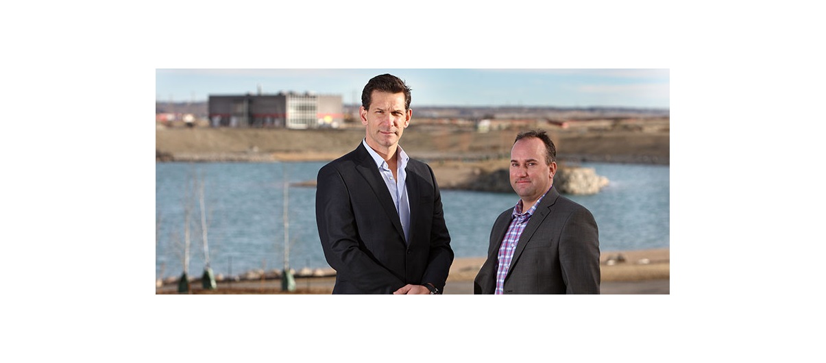 Bordeaux Properties president and CEO Birol Fisekci, left and Qualico Communities senior manager of development Cary Kienitz stand in front of Harmony's central lake, with the community’s water and wastewater treatment facilities pictured in the background. Photo by Wil Andruschak/For CREB®Now